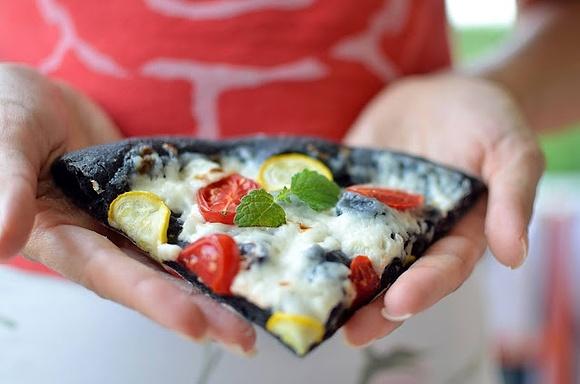 Pizza black con datterini, zucchine gialle e melissa